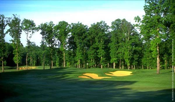 Golf course with green grass, trees, and two sand traps.