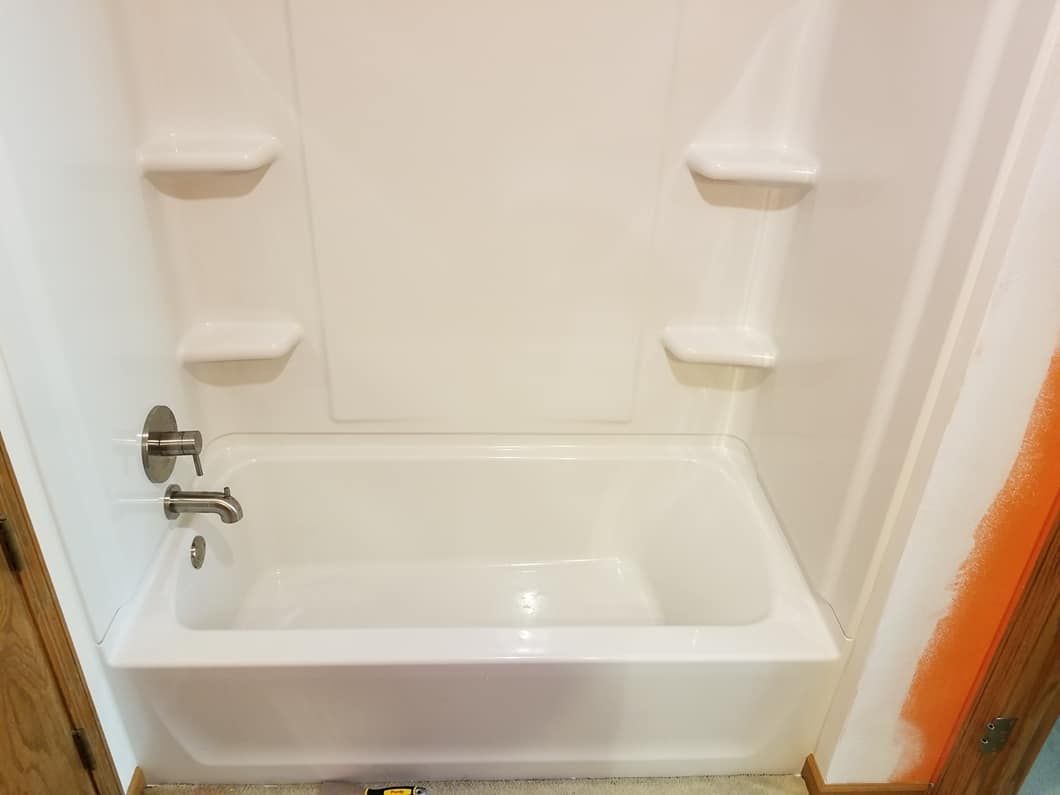 White alcove bathtub with integrated shelves and fixtures.