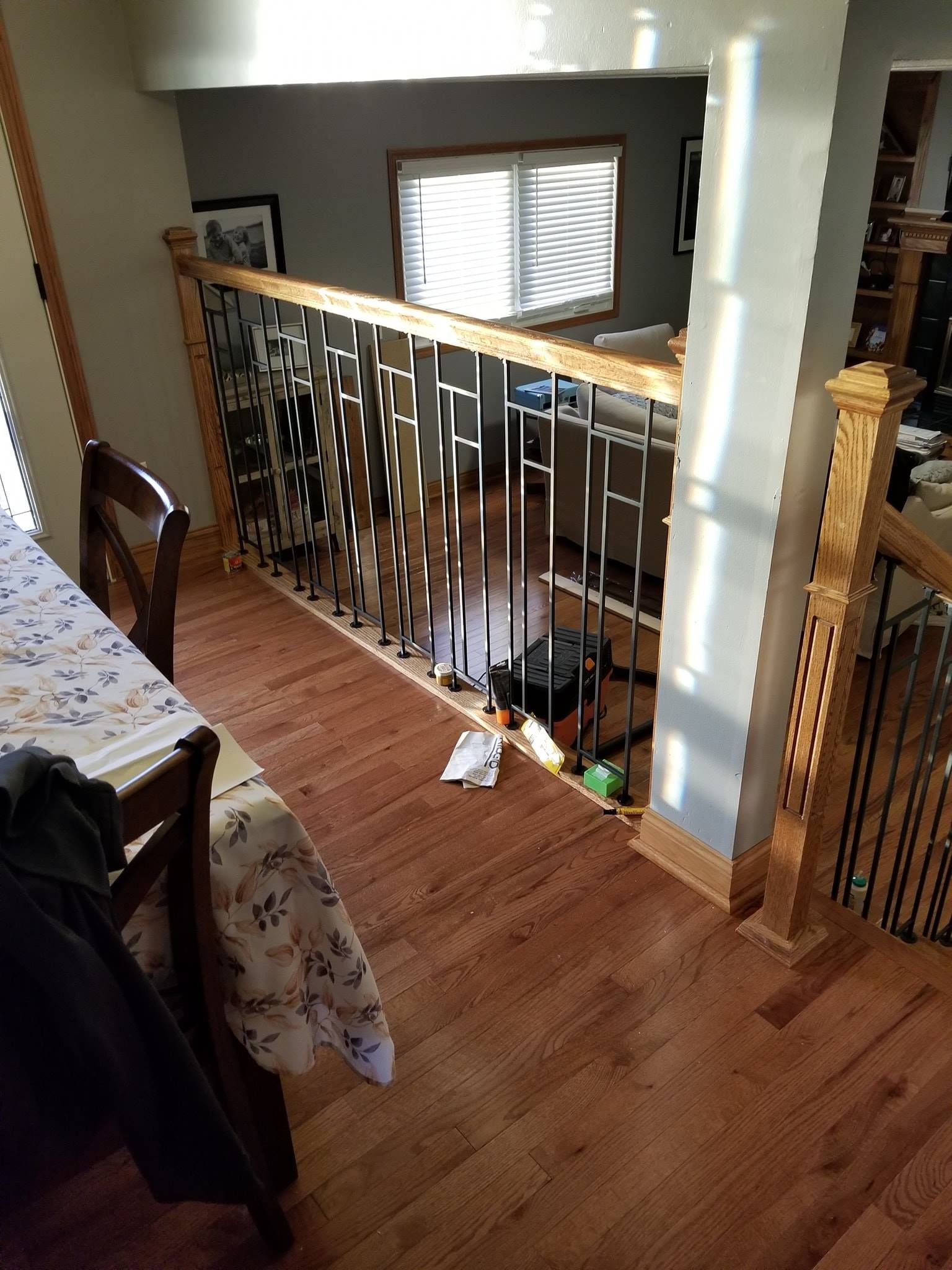 Wooden staircase with black metal railing. Light streams in from the window.