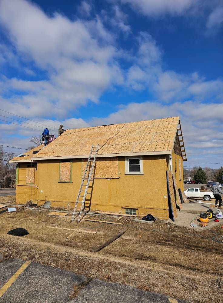 House under construction with new roof, workers, and ladder.