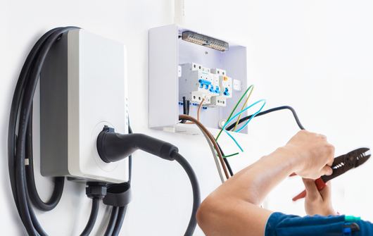 An electrician is working on an electrical box on a wall.
