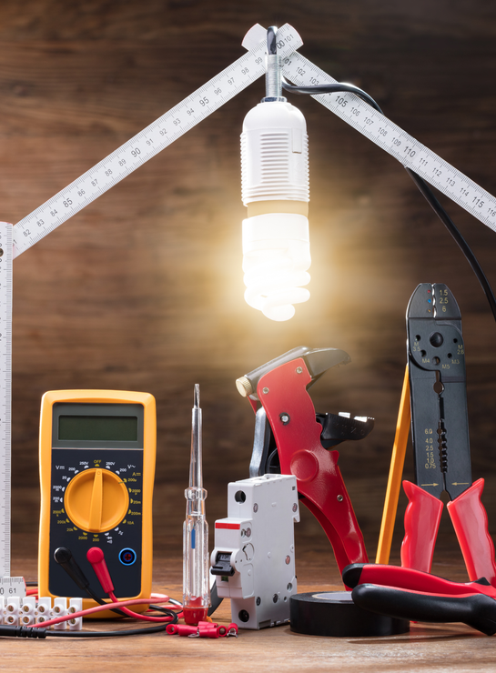 A bunch of electrical tools are sitting on a wooden table.