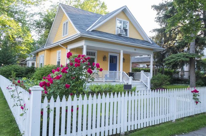 Yellow house with white picket fence and pink roses.