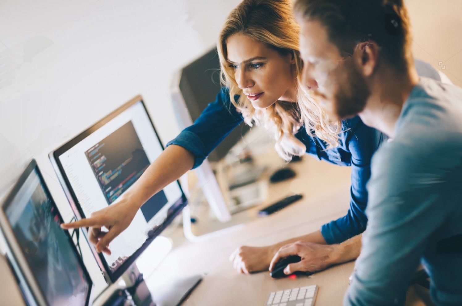 A man and a woman are looking at a computer screen.