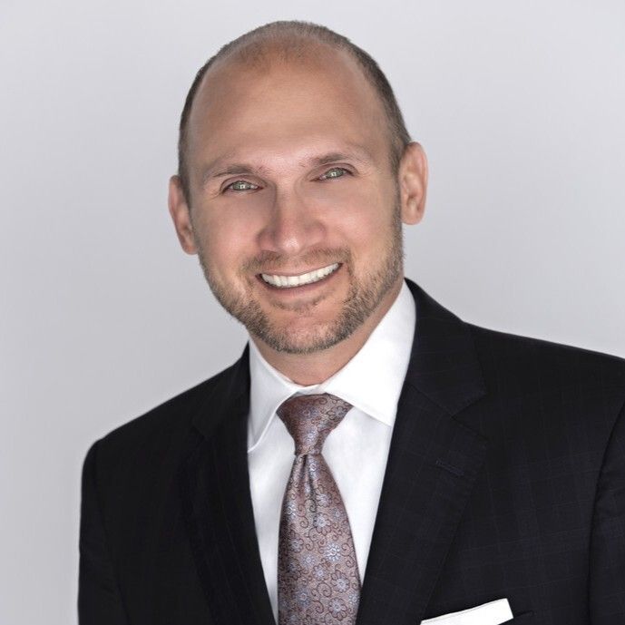 A man in a suit and tie is smiling for the camera