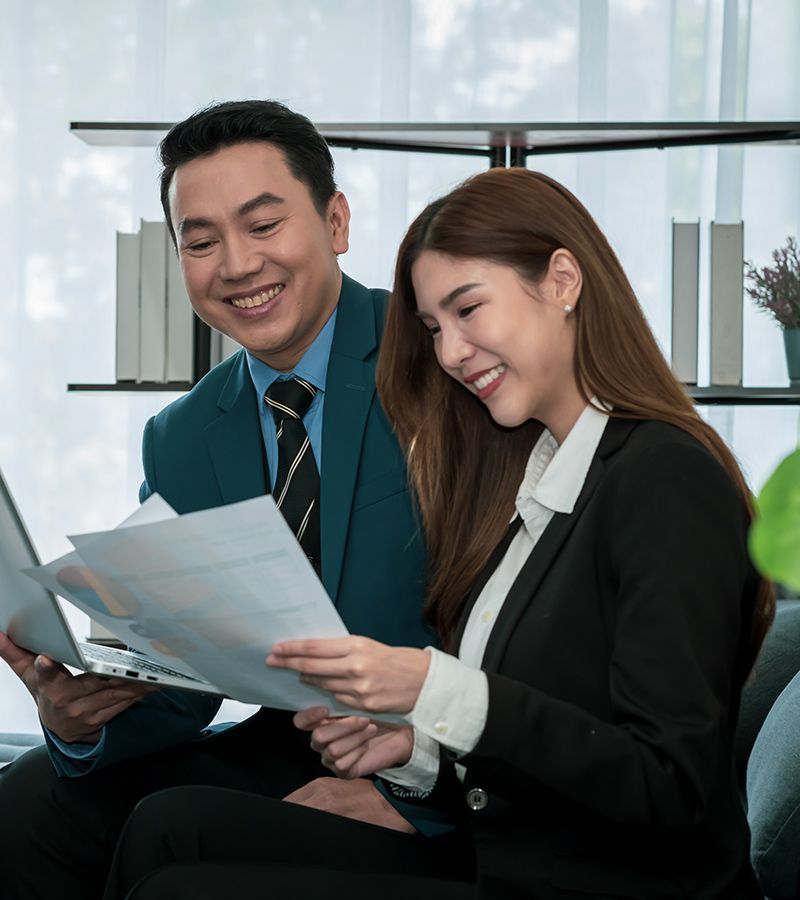 A man and a woman are sitting on a couch looking at papers.