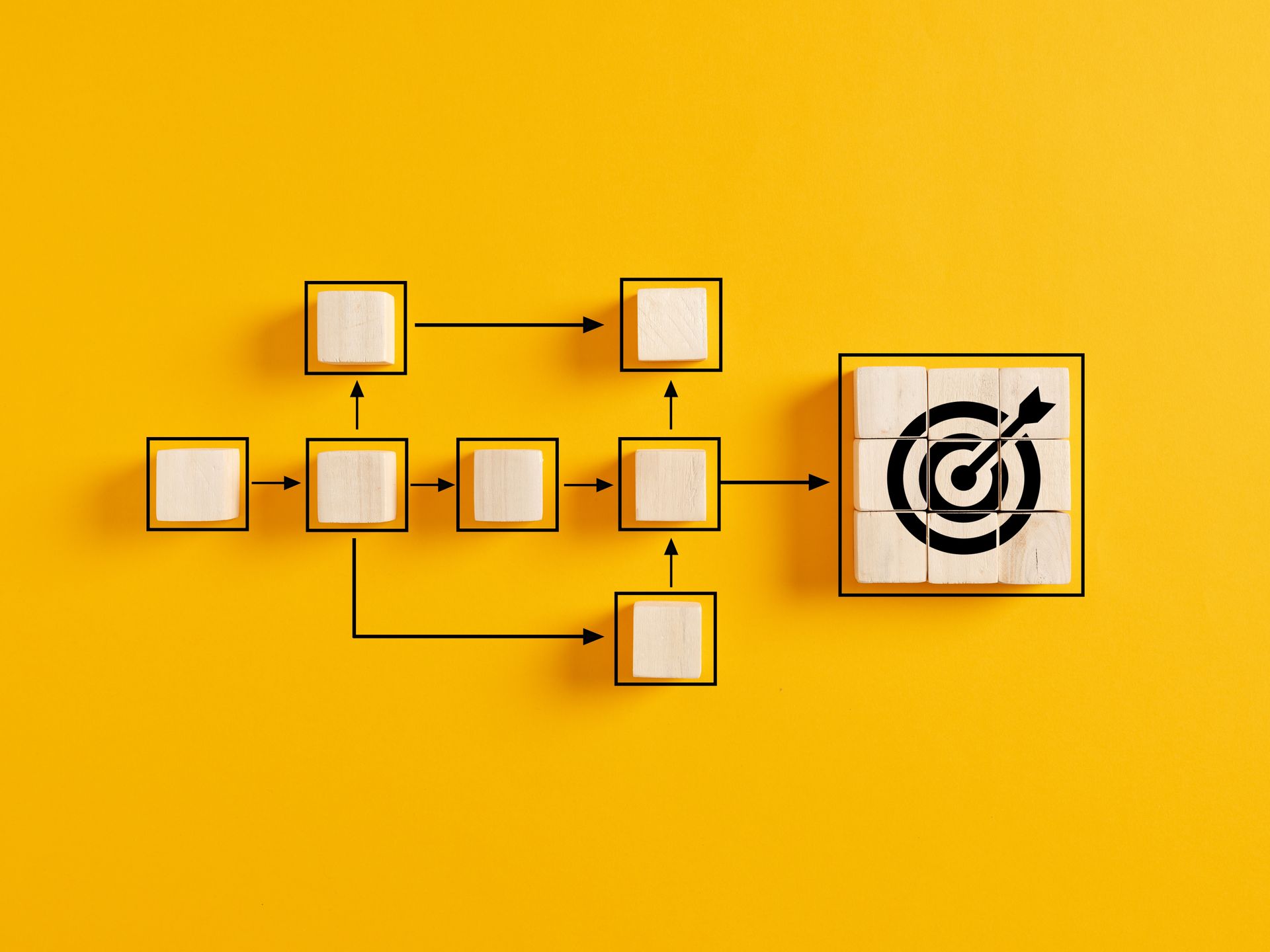 A wooden block with a target and arrow on it on a yellow background.