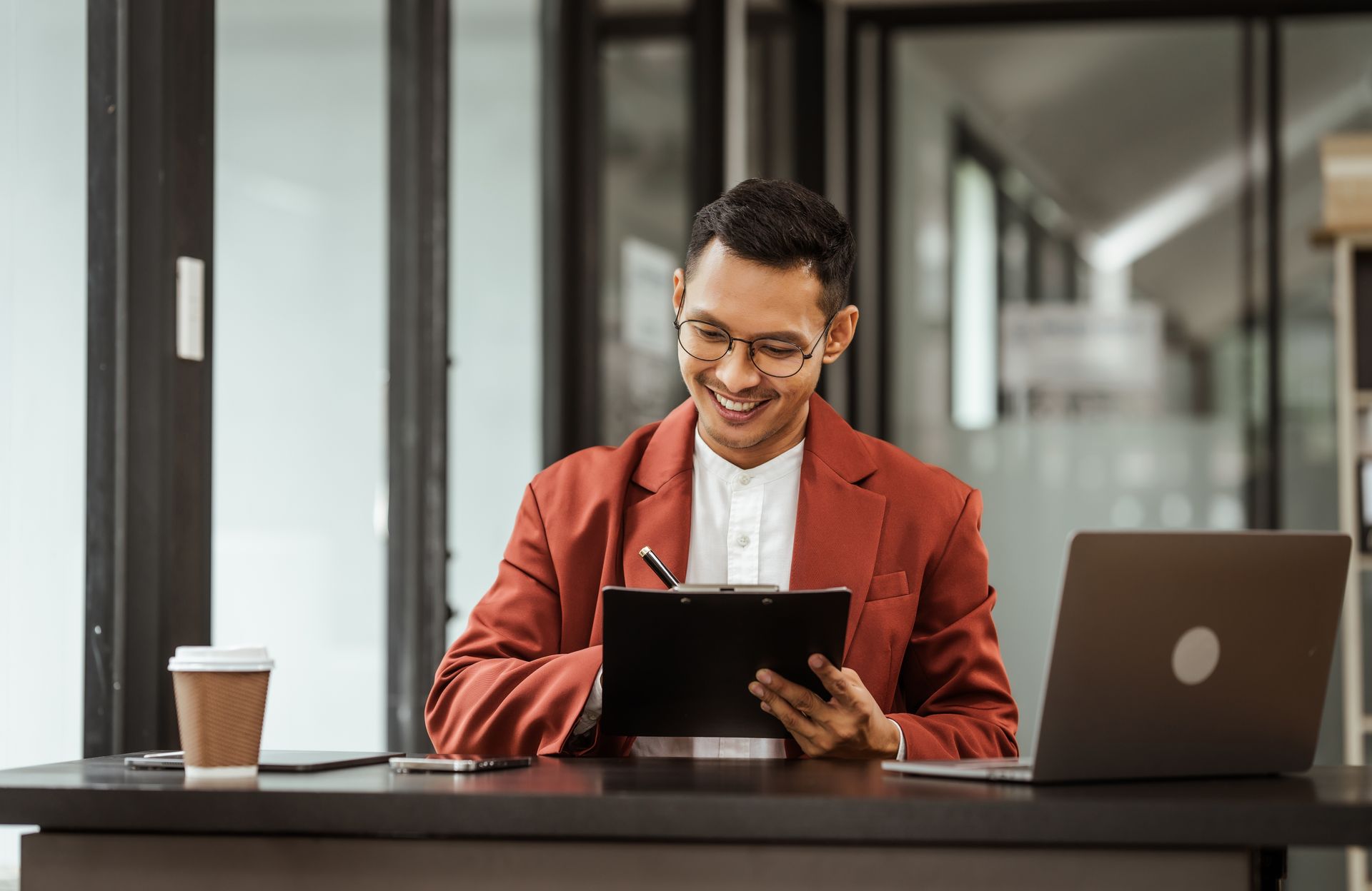 A man is sitting at a desk with a laptop and a tablet.