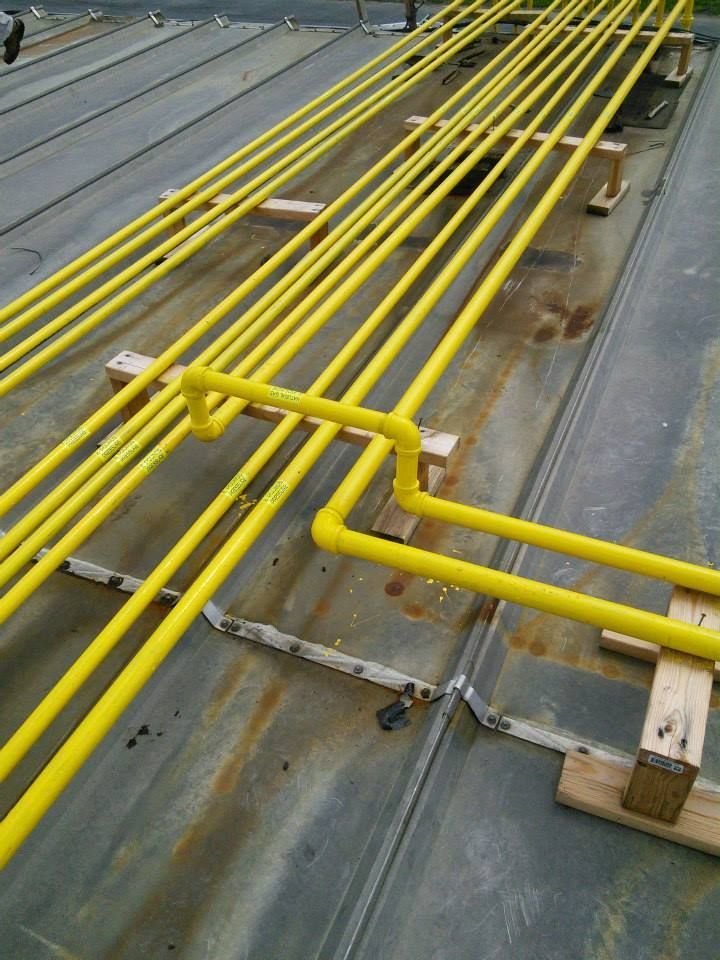 A bunch of yellow pipes are sitting on a roof