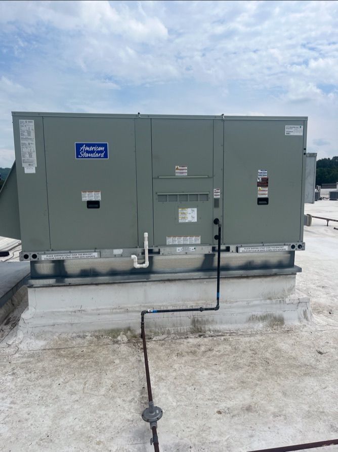 Large gray industrial HVAC unit on a concrete rooftop under a cloudy sky.