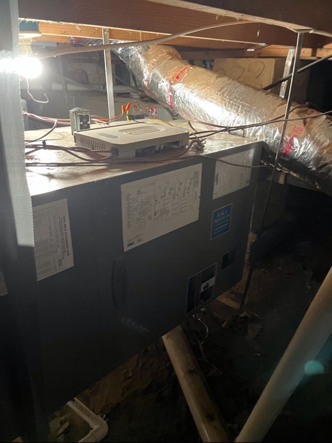 Attic HVAC unit with silver ducting, wiring, and exposed wooden beams