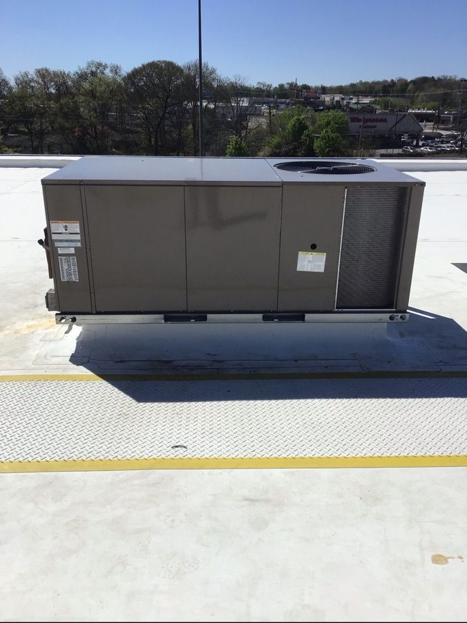 An air conditioner is sitting on top of a concrete roof.