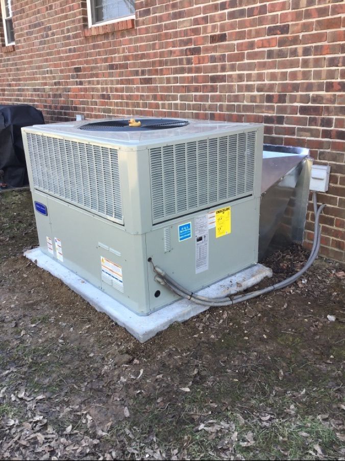 A large air conditioner is sitting on the side of a brick building.