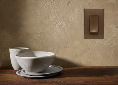 White ceramic bowls and cups on a wooden table beside a beige wall with a light switch.
