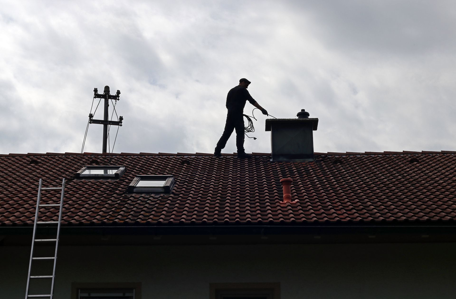 A chimney sweep cleans the chimney on a house roof