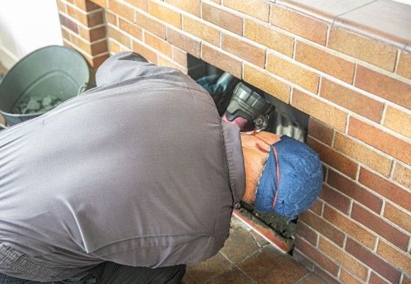 A person inspecting or repairing a small rectangular opening