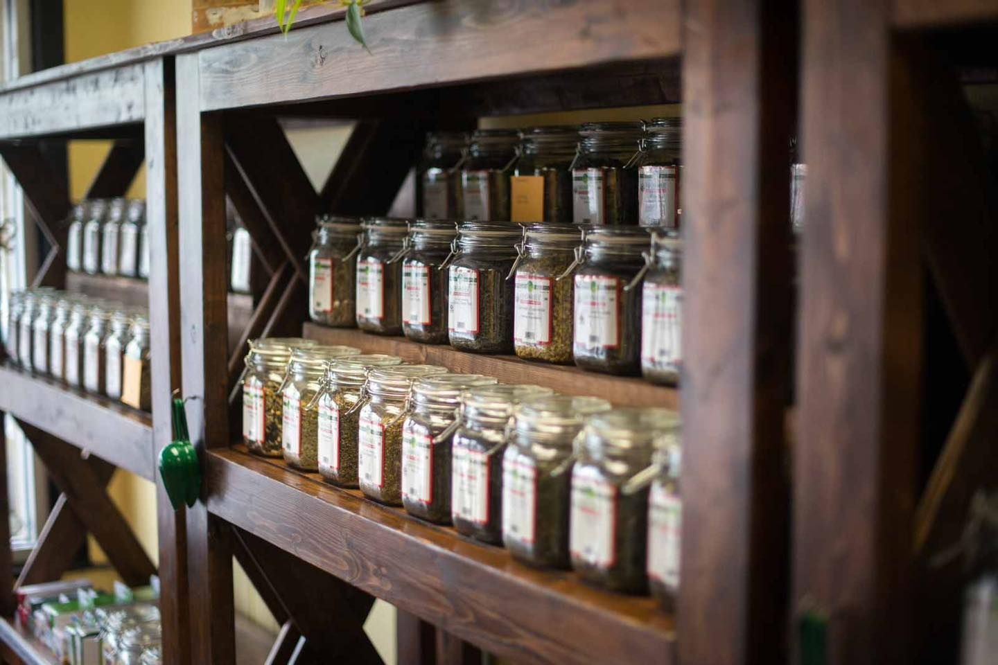 Wooden shelves filled with glass jars containing tea or spices, in a shop.