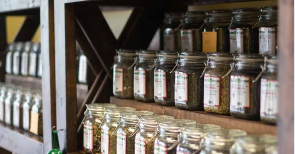 Shelves with rows of glass jars filled with various herbs and spices.