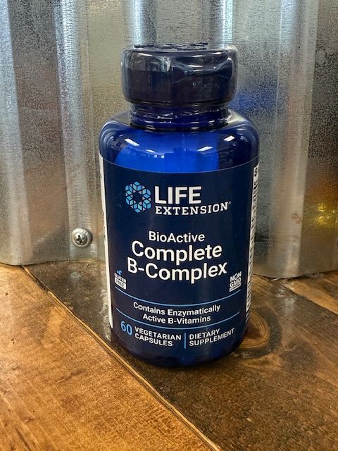 Blue bottle of Life Extension BioActive Complete B-Complex vitamin supplements on a wooden surface.