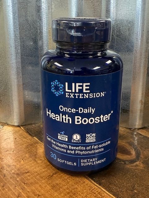 Blue bottle of Life Extension Once-Daily Health Booster supplements on a wooden surface.