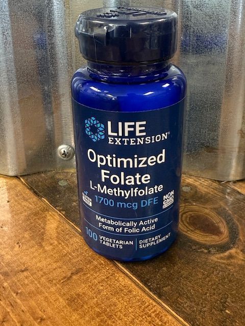 Blue bottle of Life Extension Optimized Folate L-Methylfolate 1700 mcg DFE, vegetarian tablets, on a wood surface.