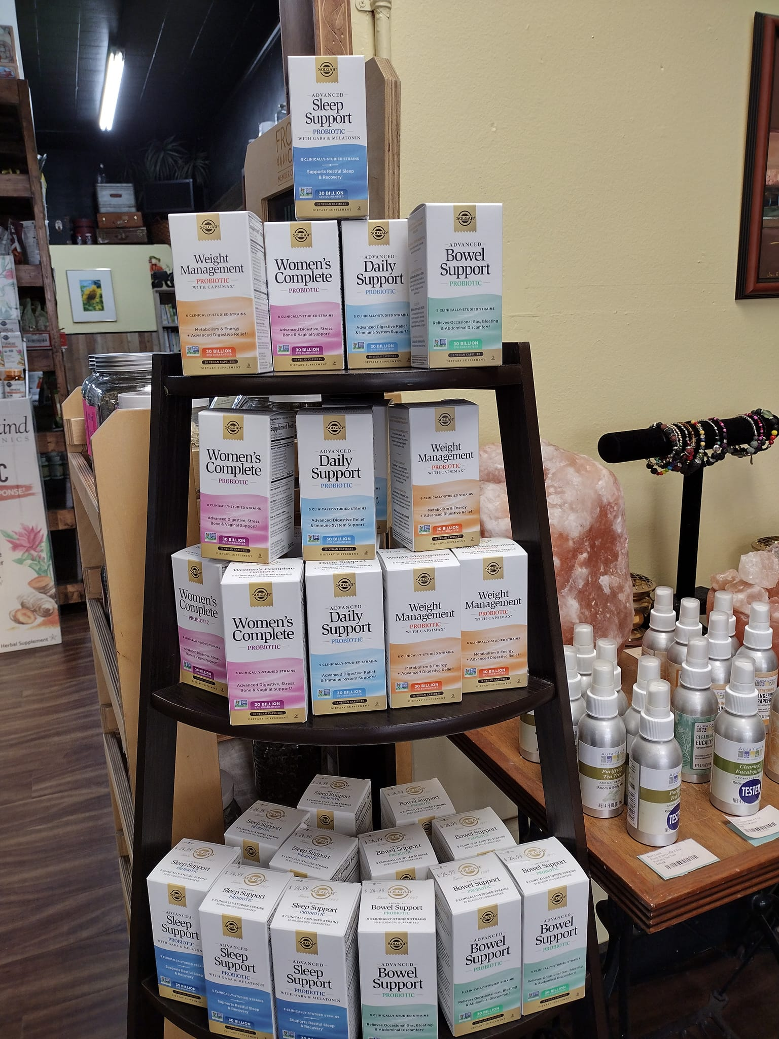Wooden shelf displaying various boxed products in a shop setting. Products have different colored labels.