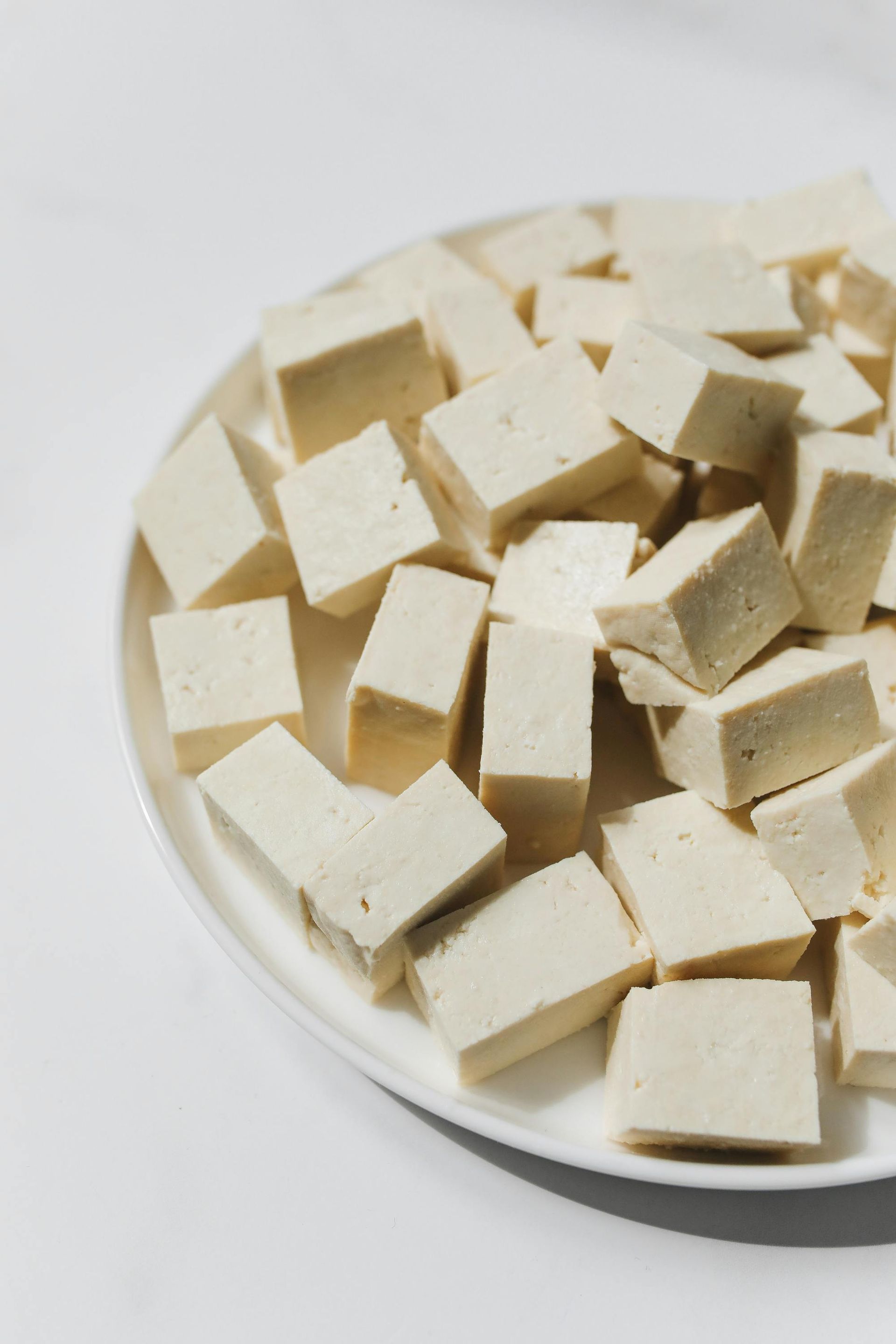 Cubed tofu on a white plate, set against a white background.