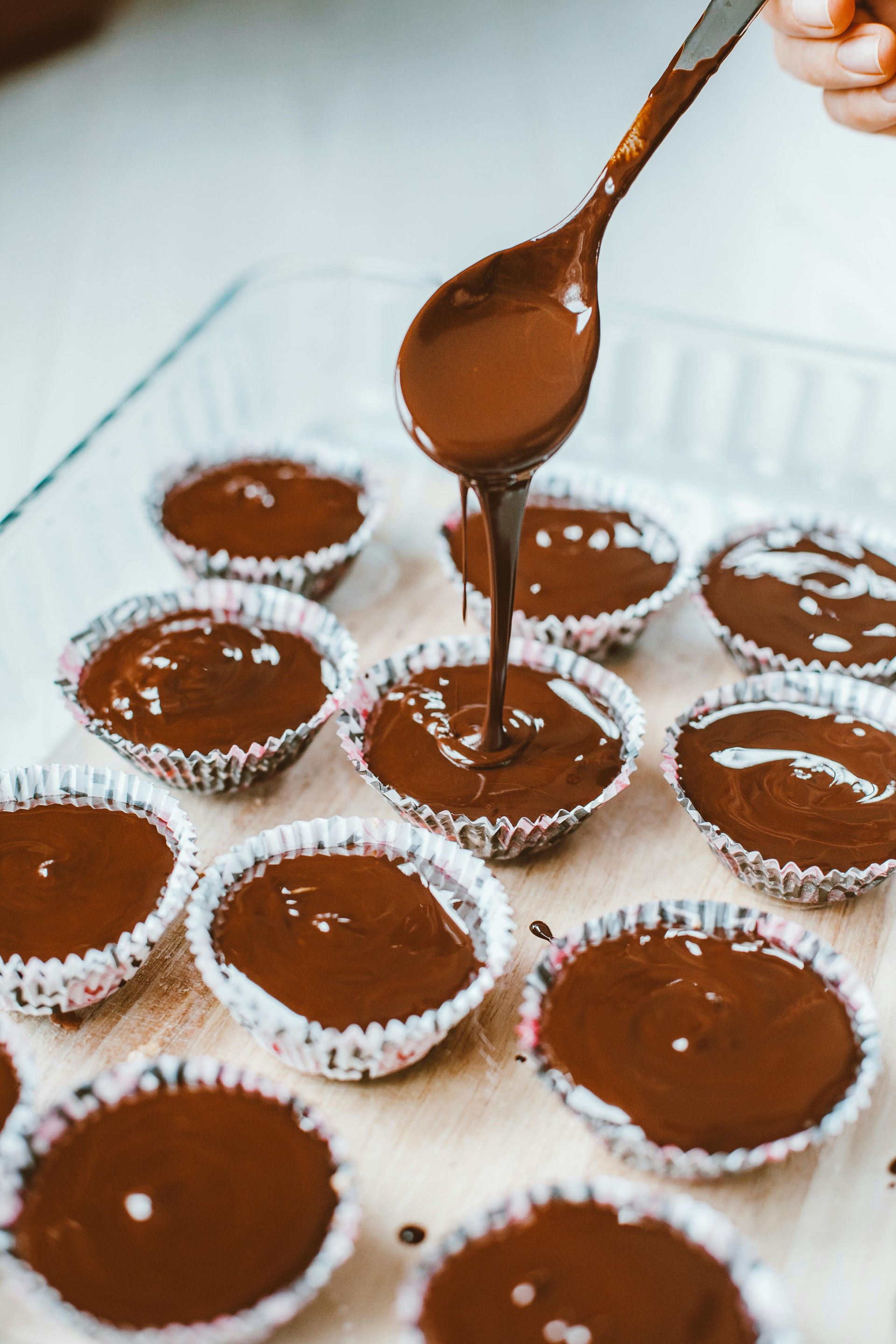 Chocolate batter being poured into cupcake liners.
