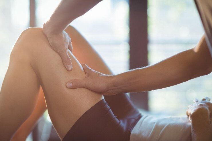 Des mains massent la jambe d'une personne. La personne est allongée et porte un short.