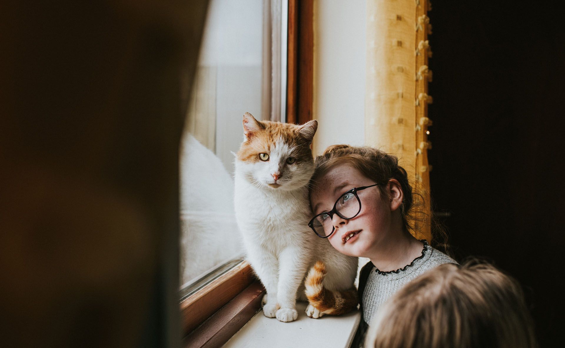 A girl is looking out lovingly towards her cat