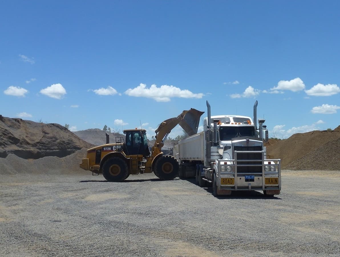 Excavator Scooping Gravel Into Truck — Quarry Products In Moranbah, QLD