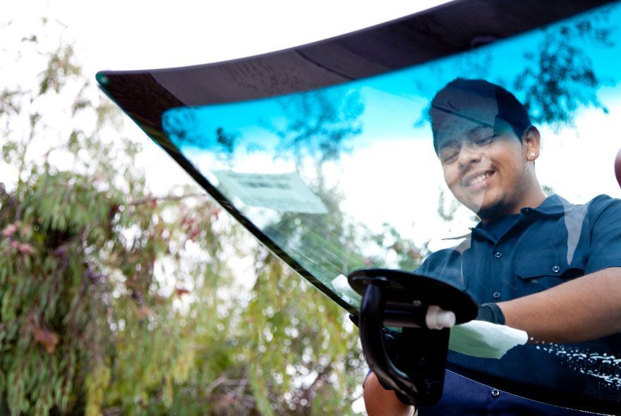 A person is fixing a broken windshield on a car.
