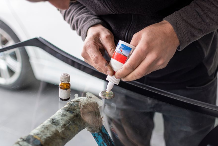 A man is fixing a windshield on a car in a garage.