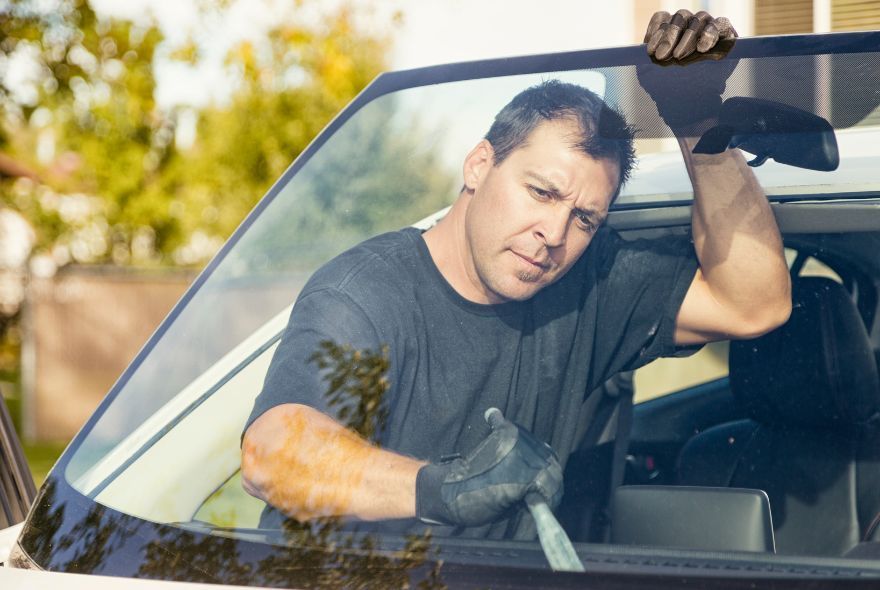 A man is fixing a windshield on a car in a garage.