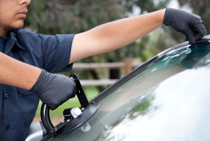 Two men are installing a windshield on a car.