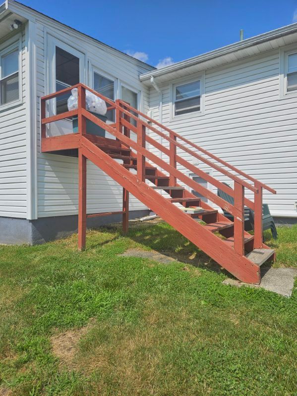 Red wooden exterior staircase leading up to a white building.