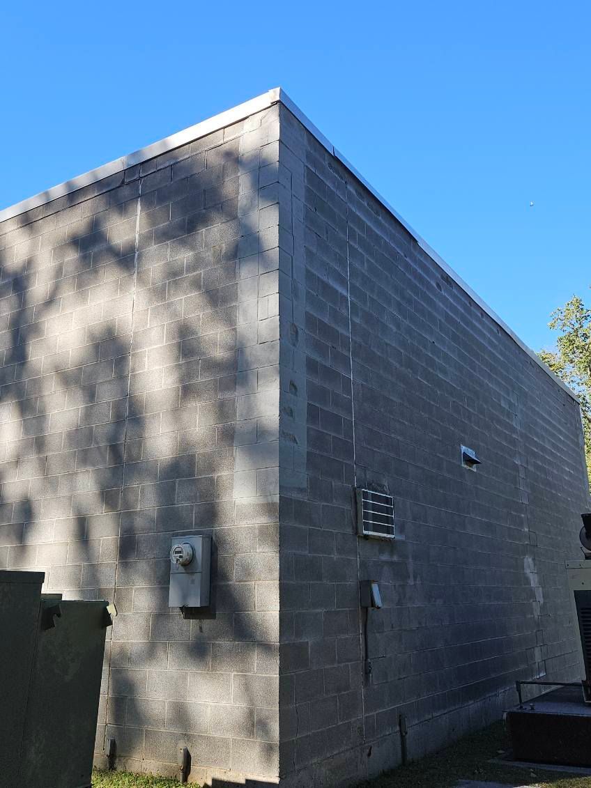 Gray cinder block building under a blue sky, electrical boxes on the wall.
