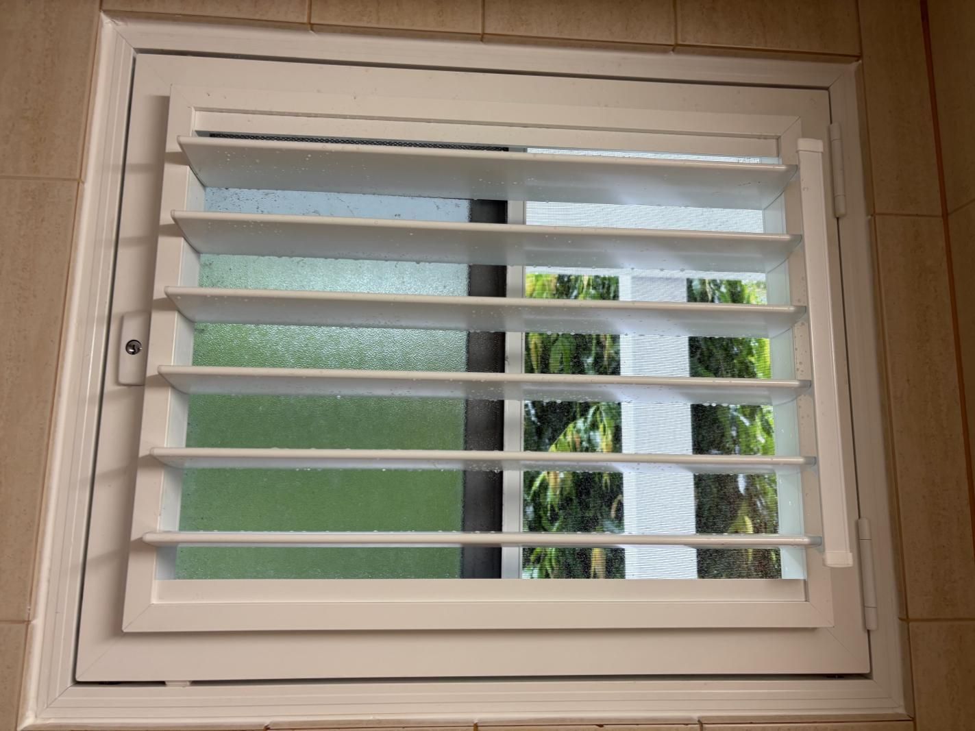 A Window With Shutters on It and a View of Trees — A1 Security Screens Cairns In Manunda, QLD