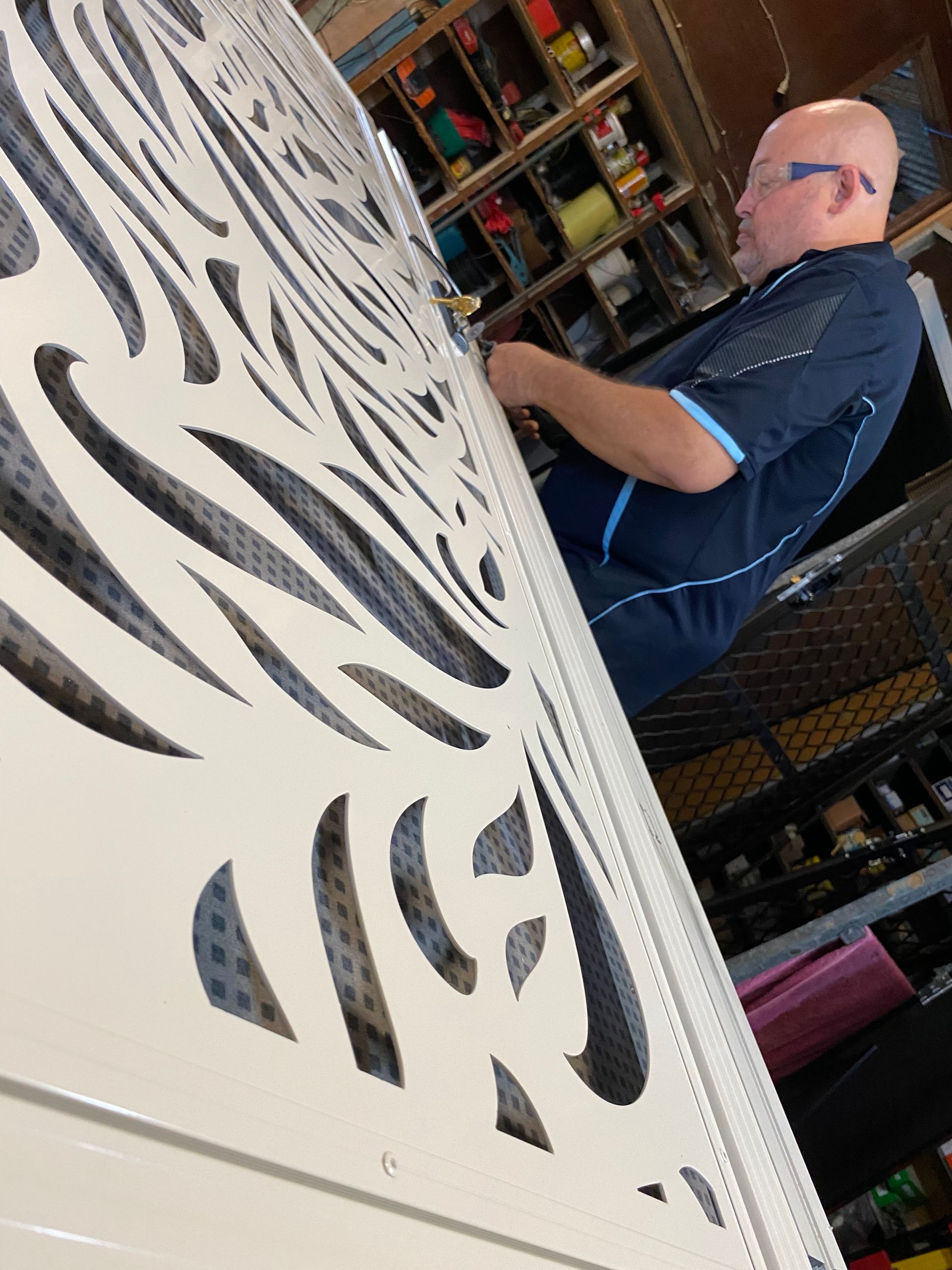 A Man in a Blue Shirt is Standing Next to a Wall With a Pattern on It — A1 Security Screens Cairns In Manunda, QLD