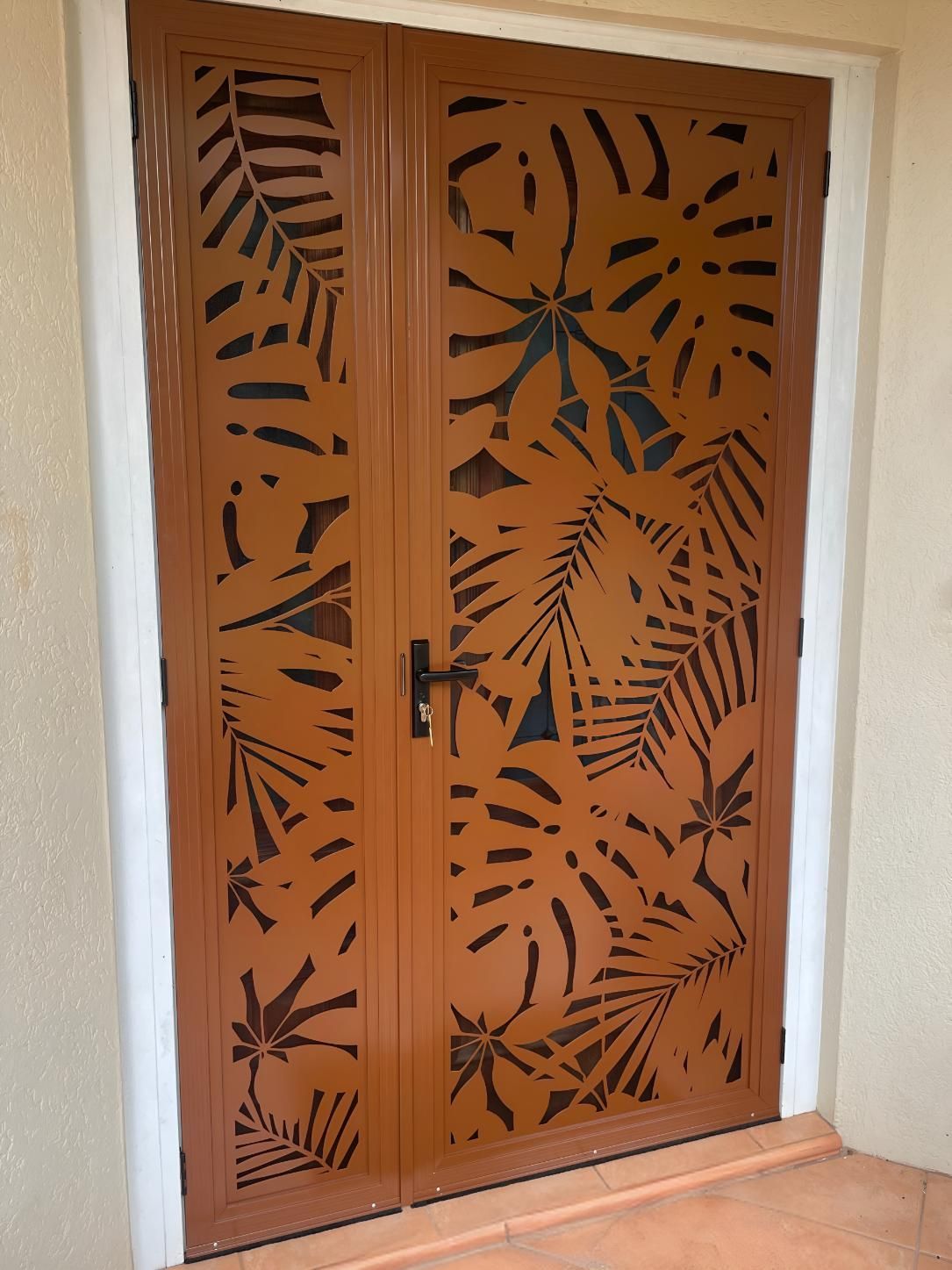 A Brown Door With a Tropical Design on It — A1 Security Screens Cairns In Manunda, QLD