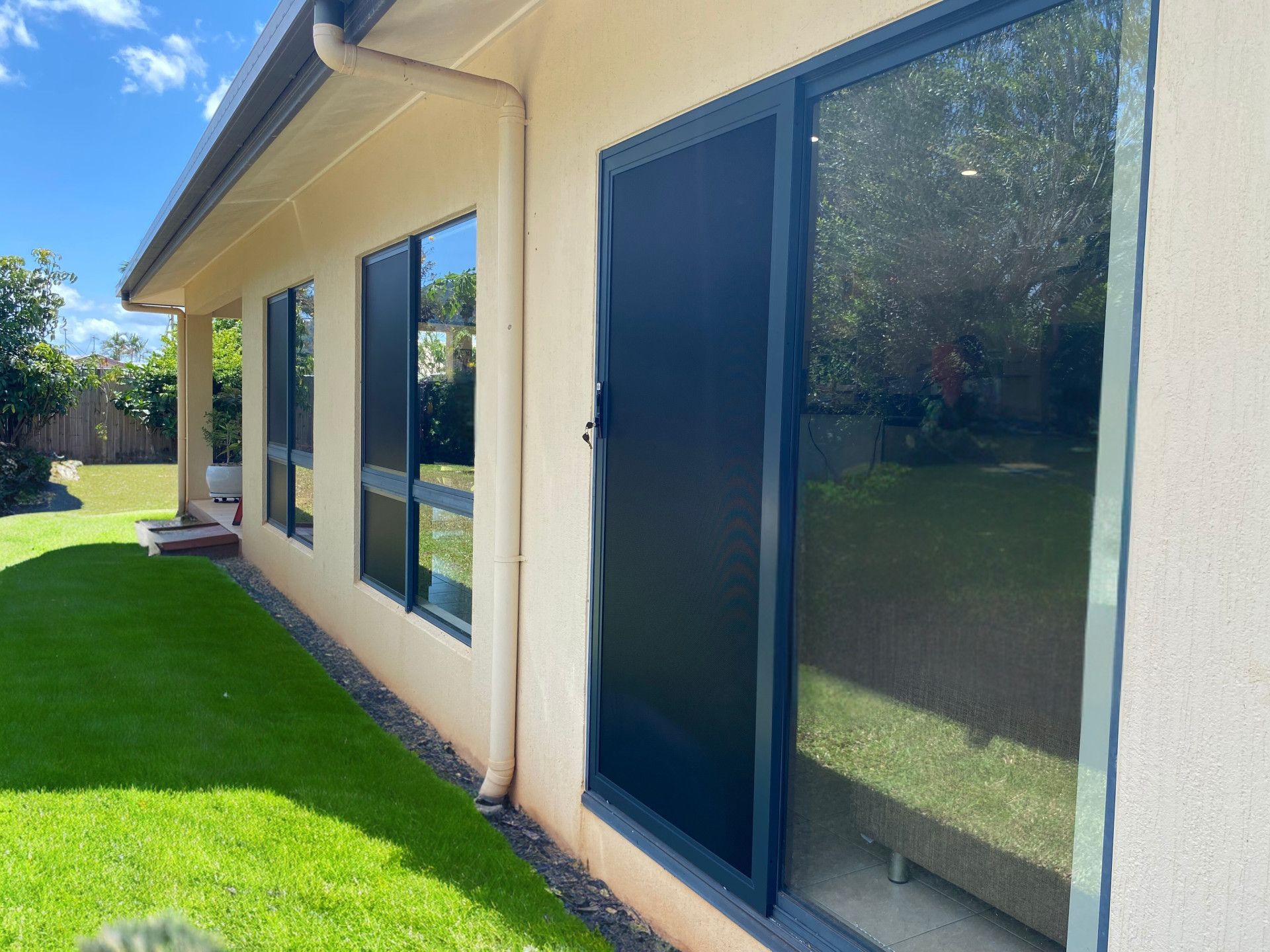 A White Door With a Black Screen on It is Open to a Brick Wall — A1 Security Screens Cairns In Manunda, QLD