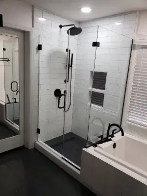 Modern bathroom with glass shower, white tub, large mirror, and tiled walls