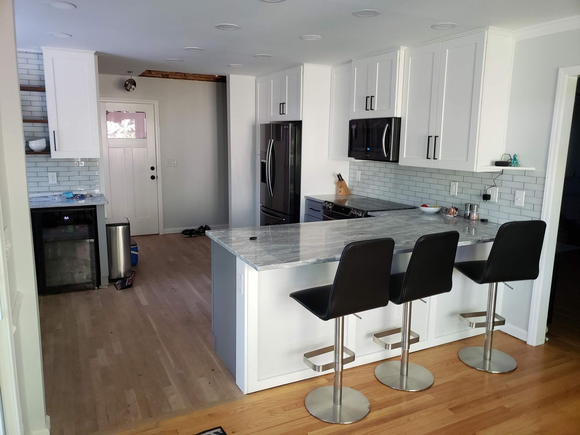 Modern kitchen with white cabinets, black bar stools, and an island in an open living space