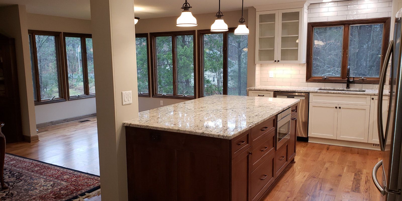 Bright kitchen with a large island, wood cabinets, granite counters, and windows overlooking trees
