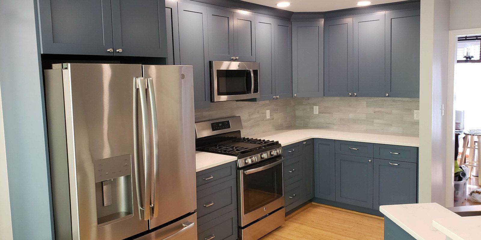 Modern kitchen with stainless steel appliances, blue cabinets, and light tile backsplash