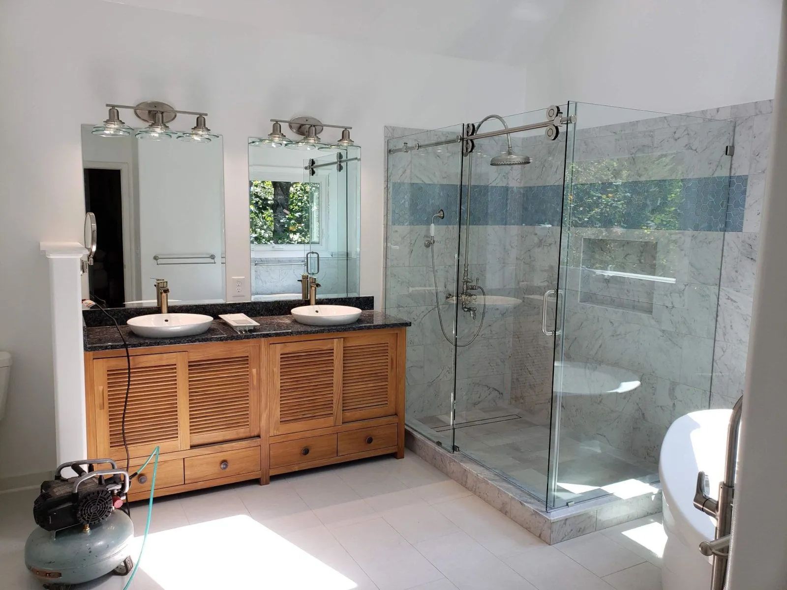 Modern bathroom with double vanity, mirrors, glass shower, and toilet on the right