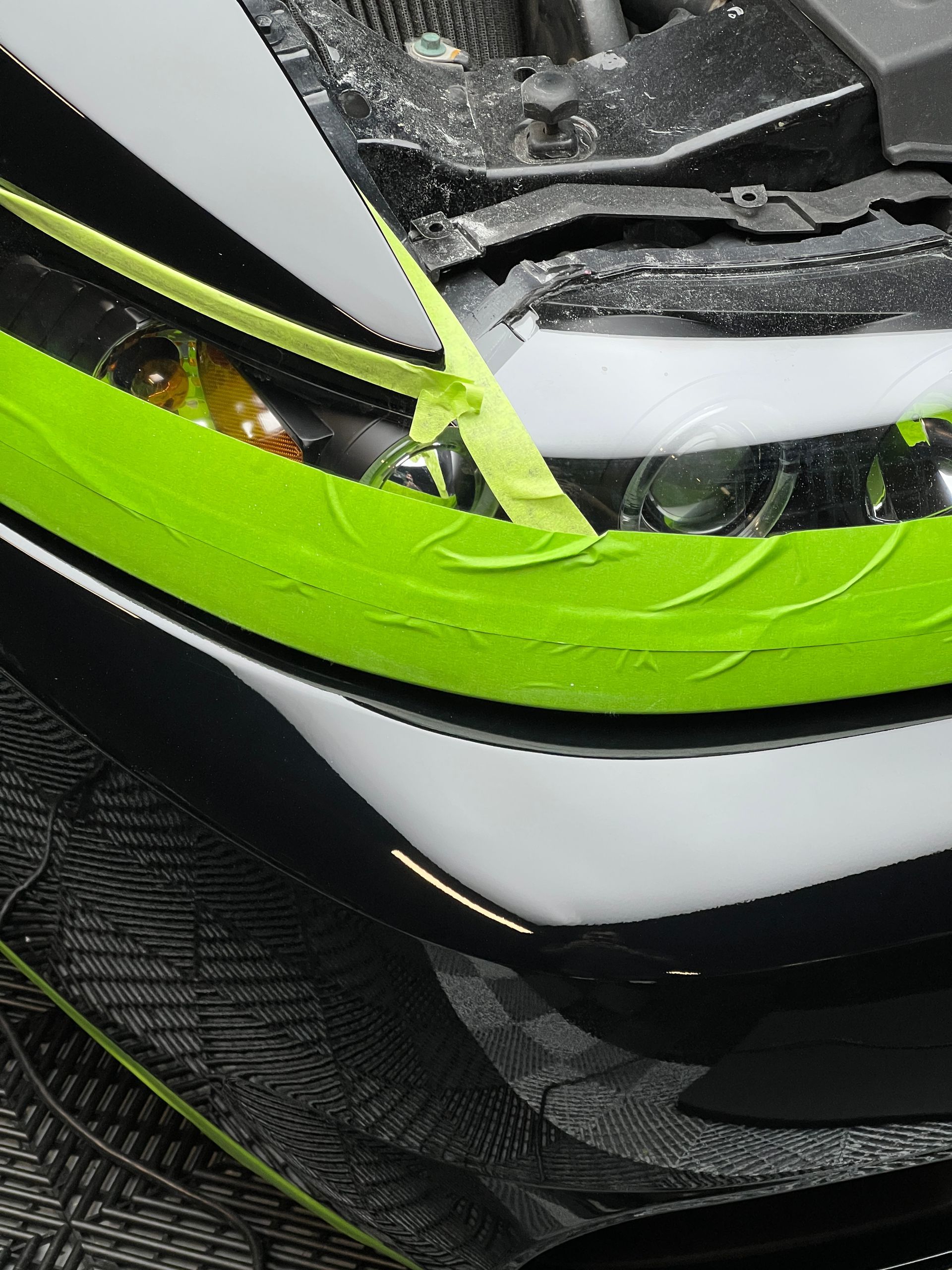A black and white car with a yellow tape covering the headlights