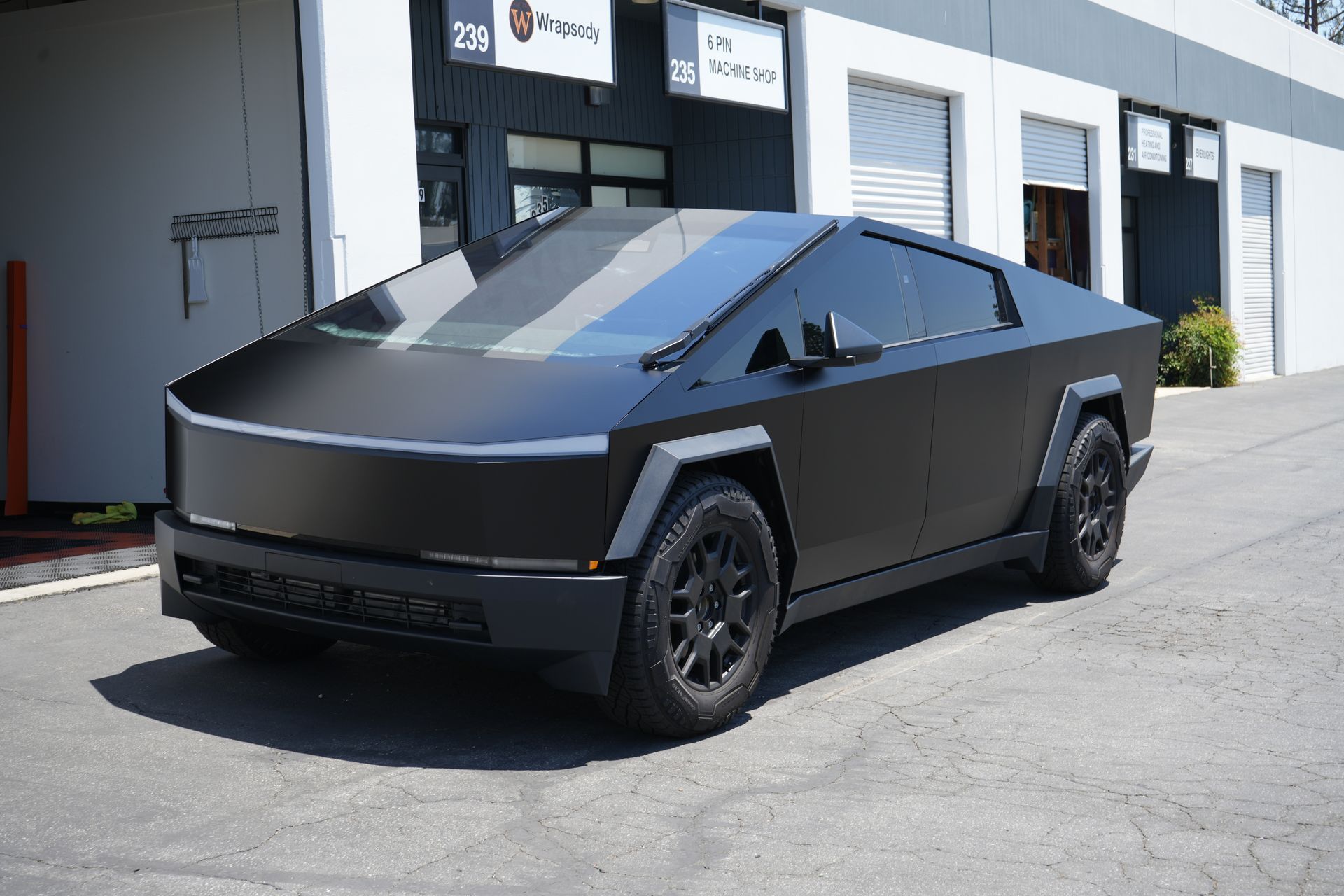 A black tesla cybertruck is parked in front of a building.
