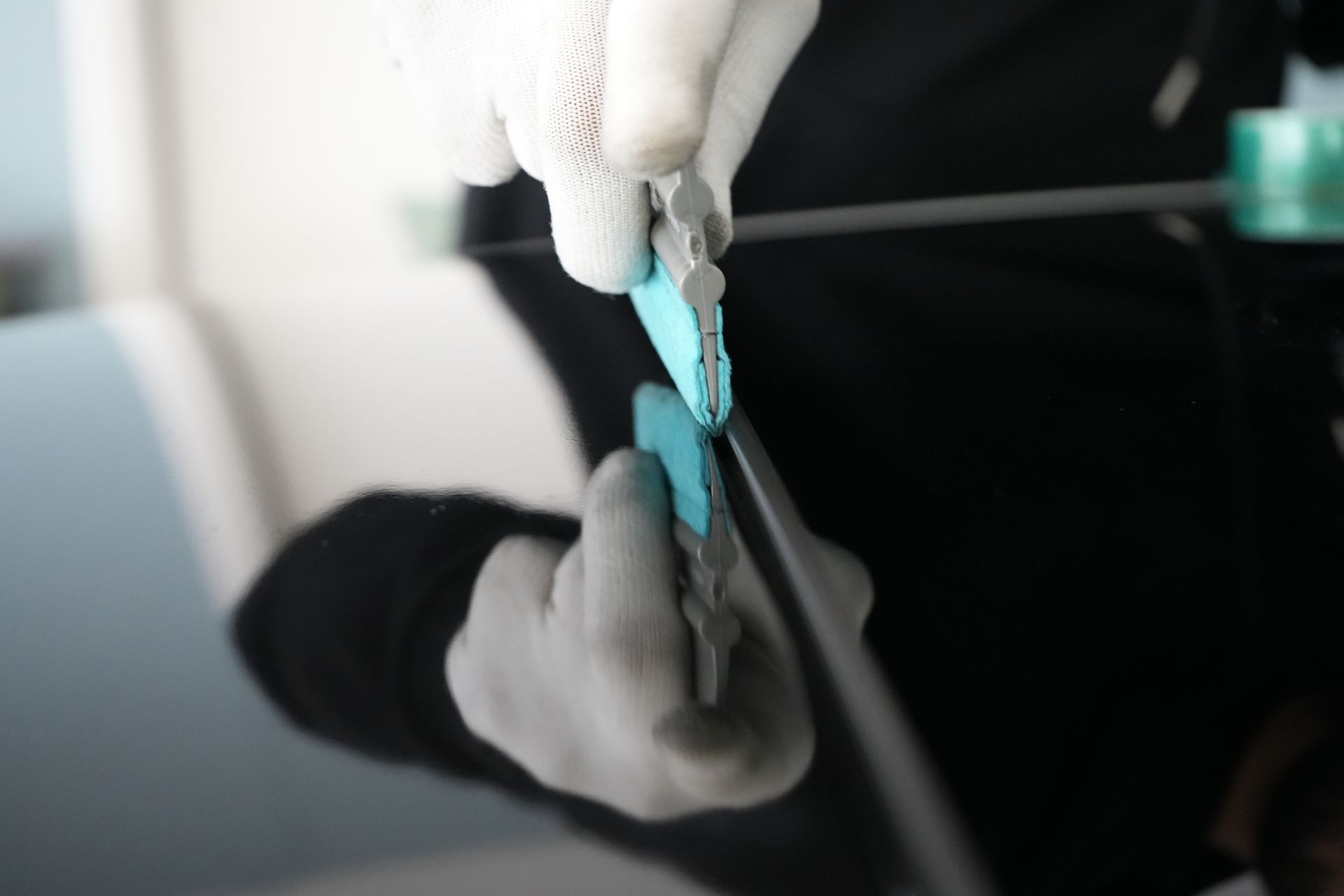 A person is cutting a piece of glass with a pair of scissors.