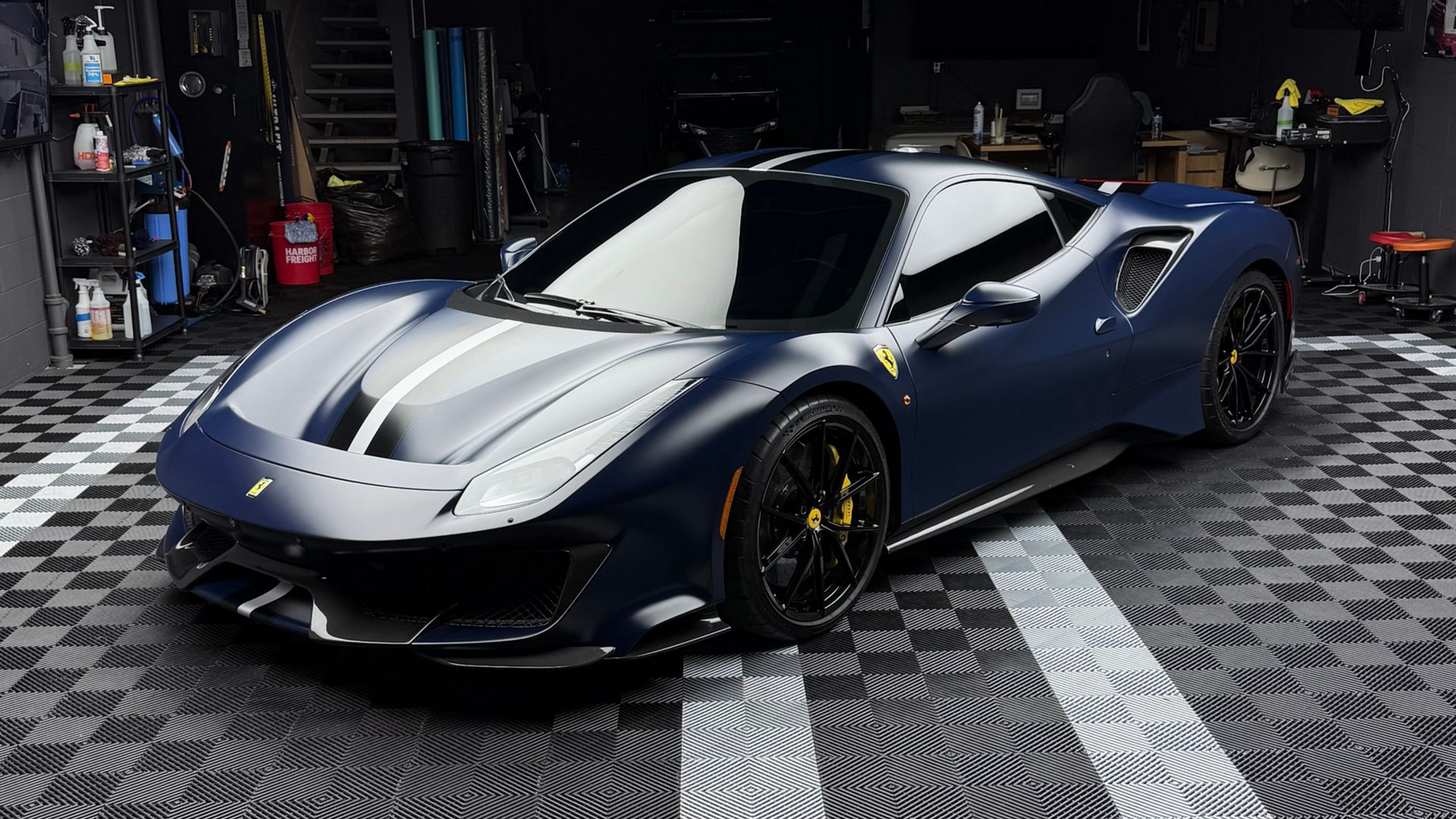 A purple sports car is parked under a bridge in a parking lot.